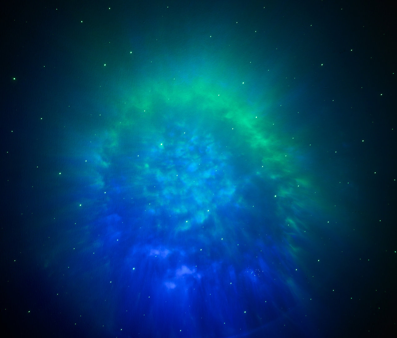 Photo floue d'un amas d'étoiles dans les tons bleus et verts.