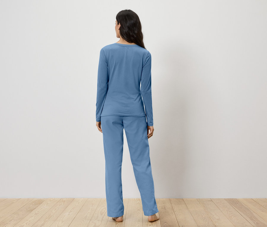 Une femme, vue de dos, porte un pyjama bleu.