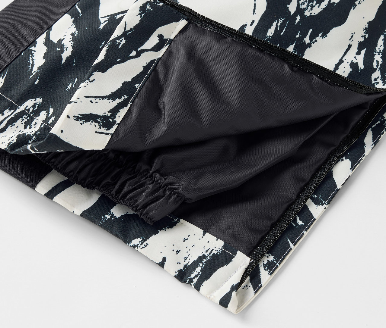 Détail d'un pantalon à motifs noirs et blancs avec une poche ouverte.