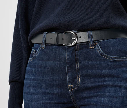 Ceinture en cuir noire sur un jean bleu.