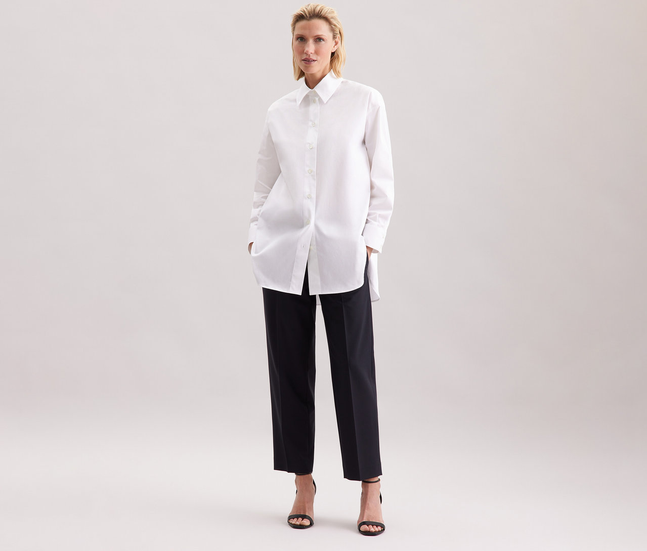 Femme portant une blouse-chemise blanche grande taille Seidensticker et un pantalon noir.