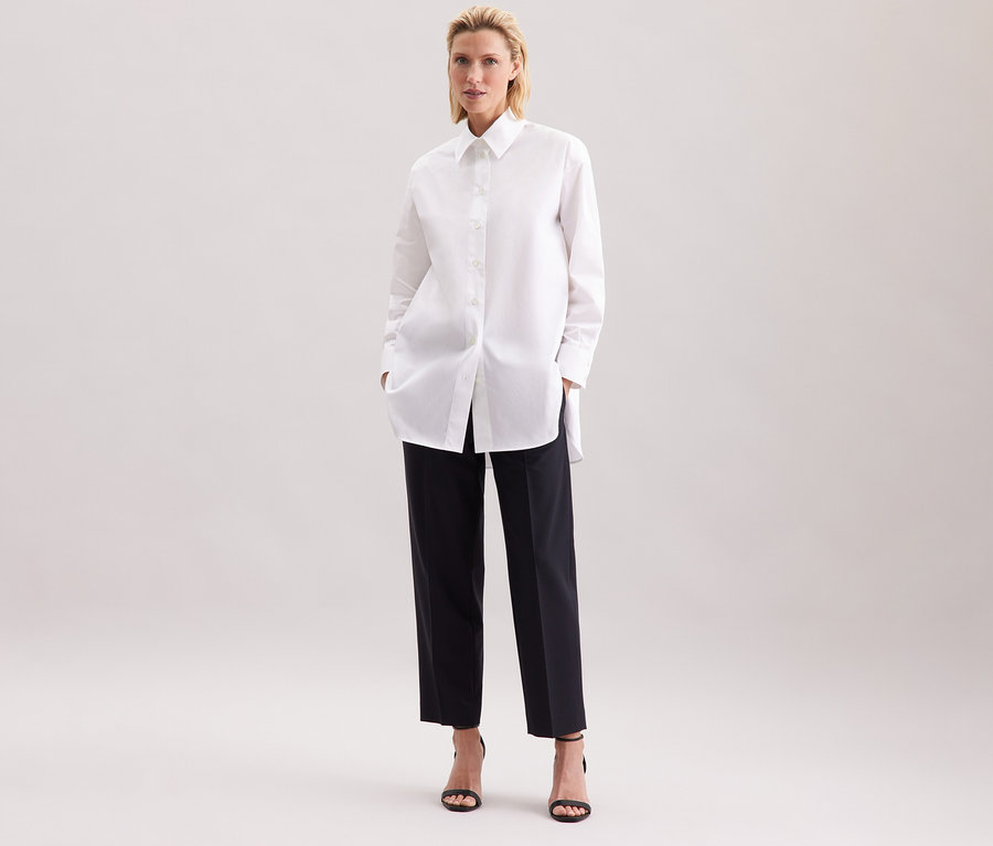 Femme portant une blouse-chemise blanche grande taille Seidensticker et un pantalon noir.