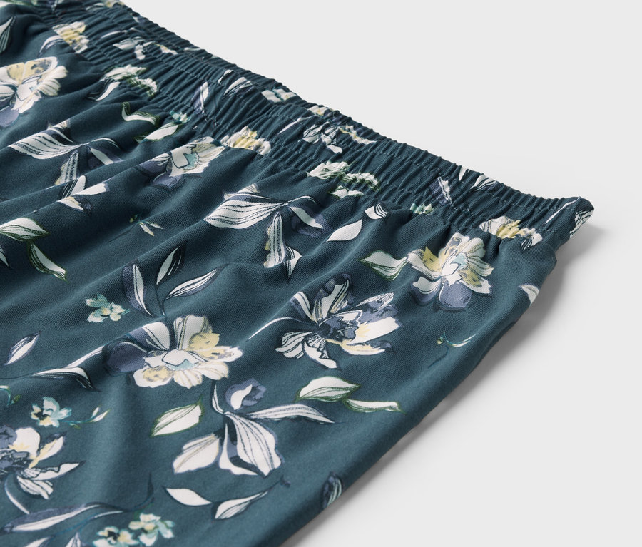 Gros plan sur la taille élastique et le motif floral d'un pantalon.