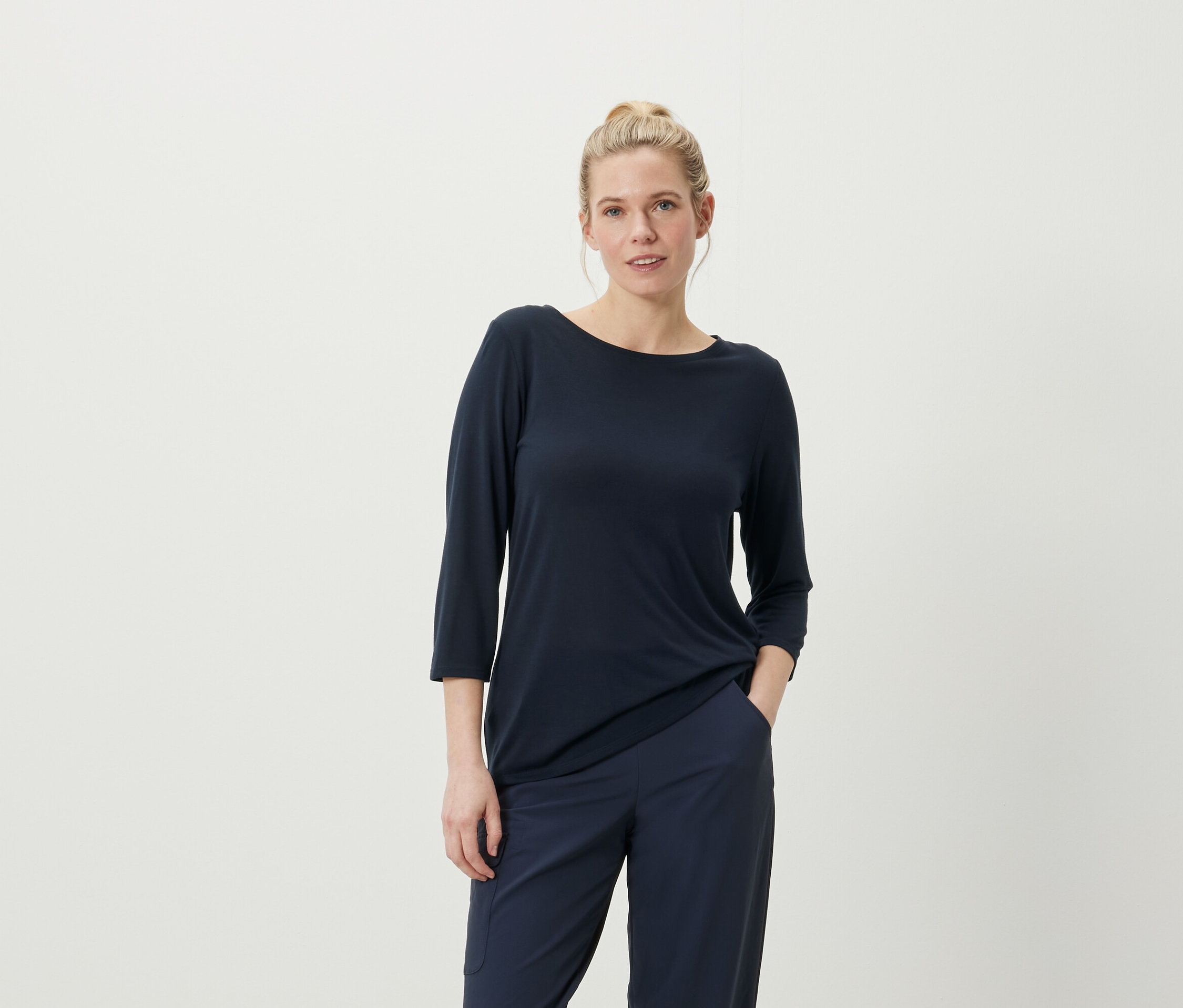 Femme posant dans un t-shirt à manches trois-quarts bleu marine et un pantalon.