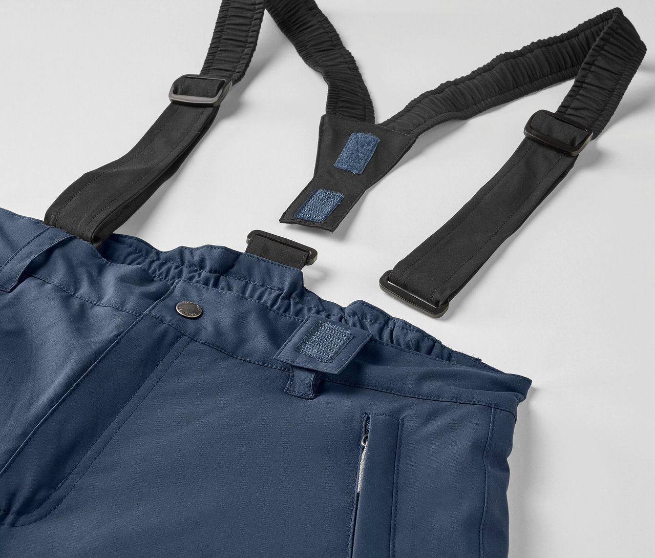 Gros plan d'un pantalon bleu avec des bretelles élastiques noires.