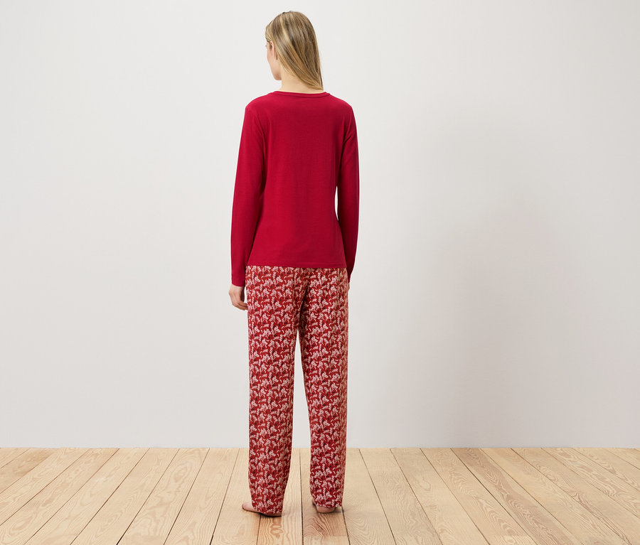 Une femme se tient dos à la caméra et porte un pyjama rouge.