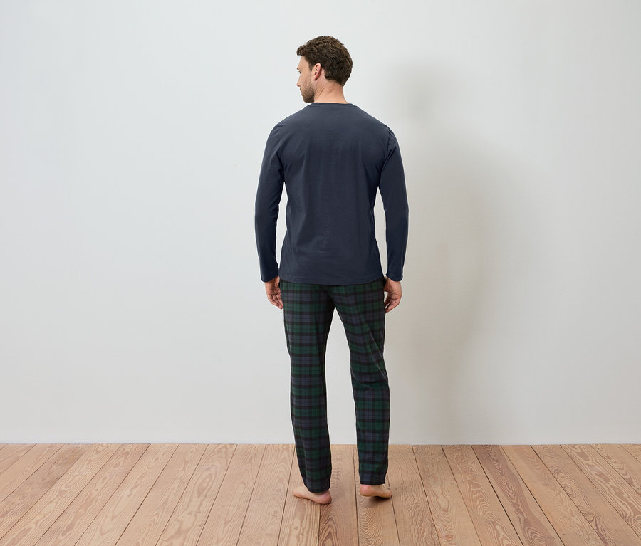 Un homme, vu de dos, porte un t-shirt de pyjama bleu marine et un pantalon de pyjama à carreaux.
