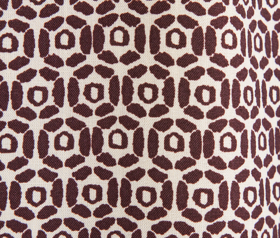 Gros plan d'un tissu avec un motif géométrique marron sur un fond beige.