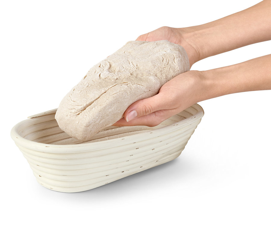 Deux mains déposent une boule de pâte à pain dans un banneton.