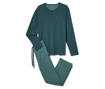 Un pyjama vert à manches longues et un pantalon à motifs sont posés sur un fond blanc.