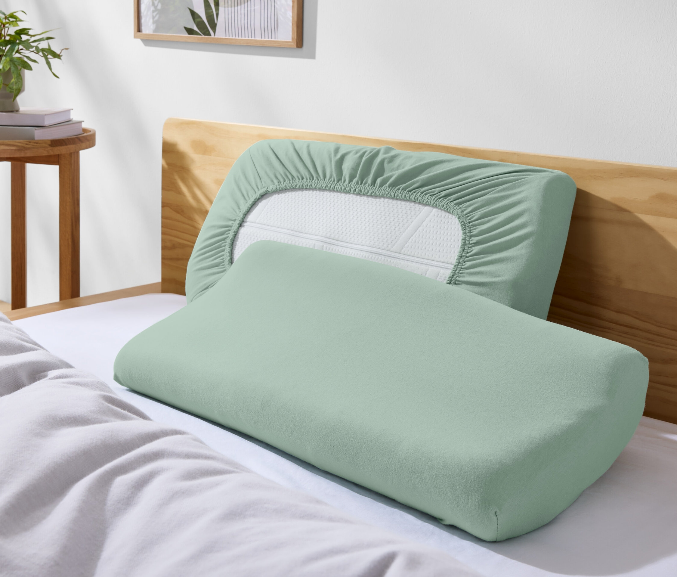 Deux oreillers verts sur un lit avec des draps blancs.