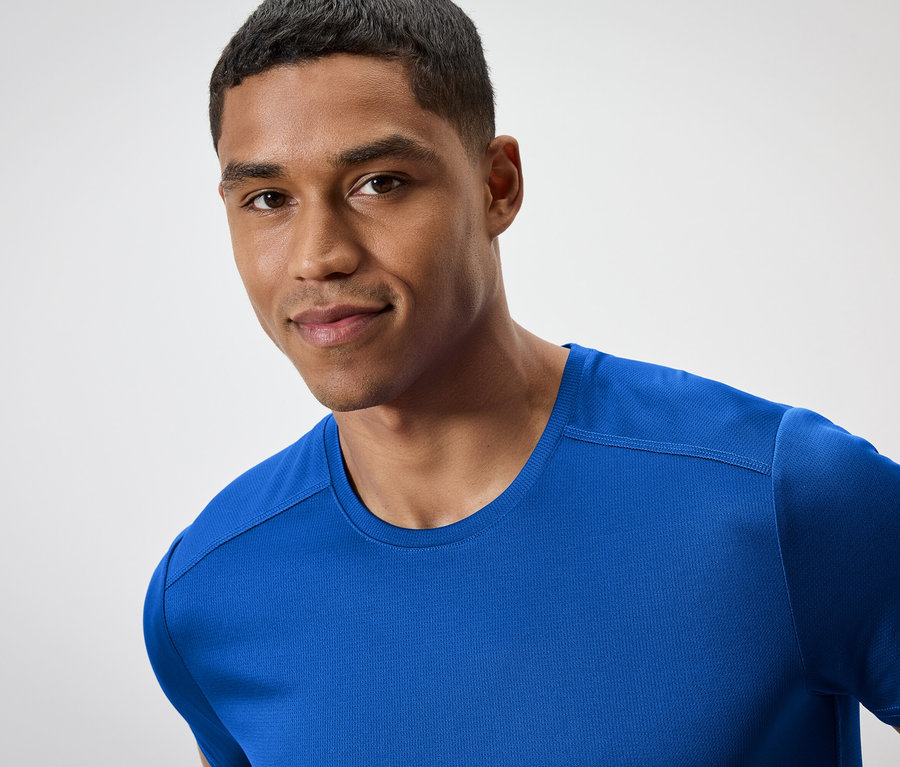 Portrait d'un homme souriant portant un t-shirt bleu.
