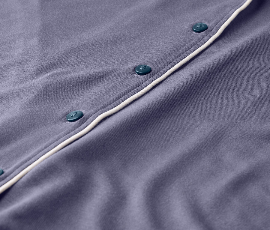 Gros plan d'un pyjama violet avec des boutons et une bordure blanche.