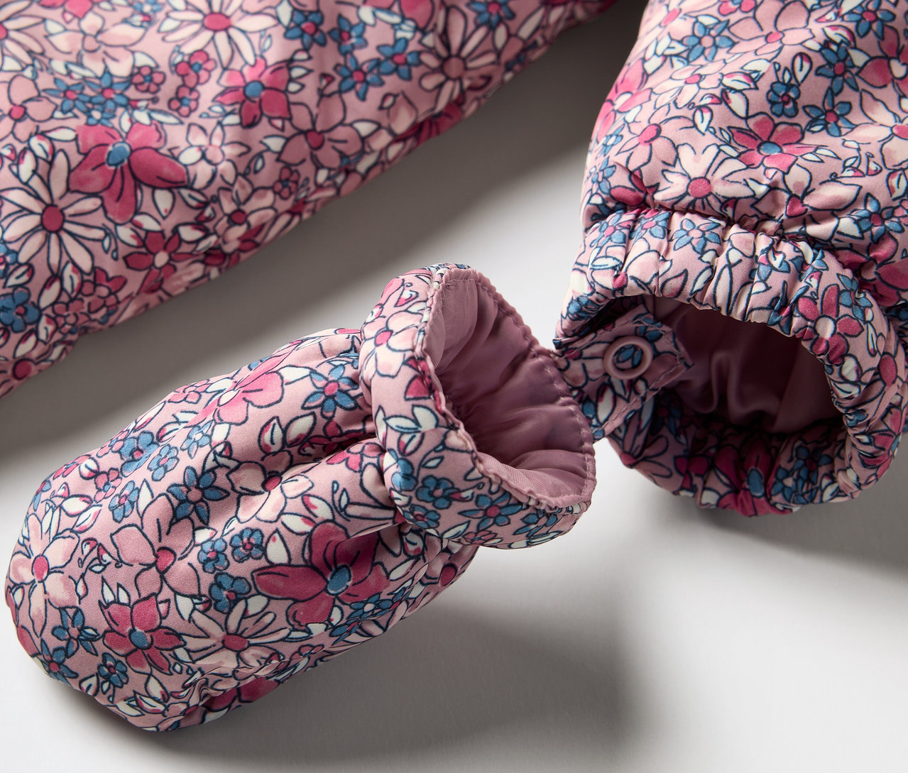 Gros plan sur une combinaison d’hiver pour bébé à motif floral avec un gant.