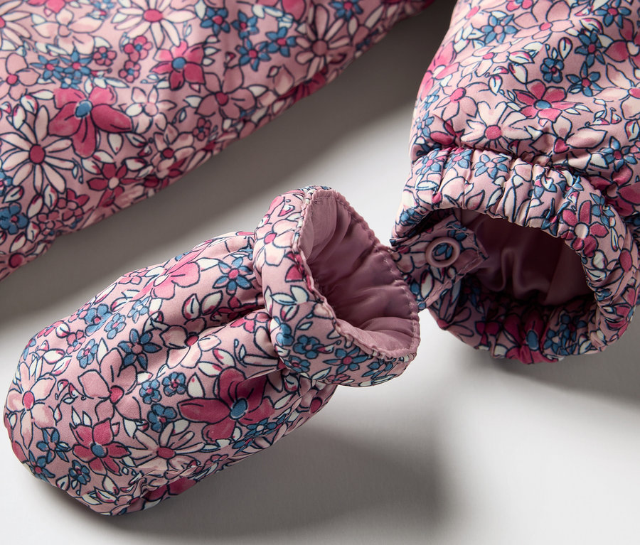 Gros plan sur une combinaison d’hiver pour bébé à motif floral avec un gant.