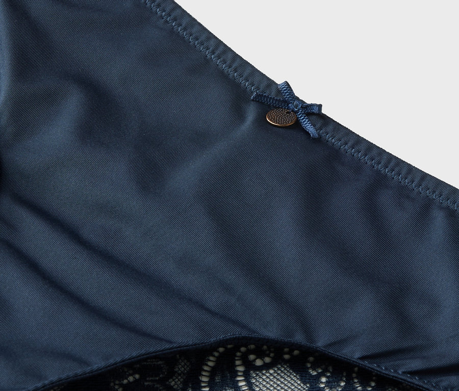 Gros plan sur une culotte bleu foncé avec de la dentelle et un nœud.