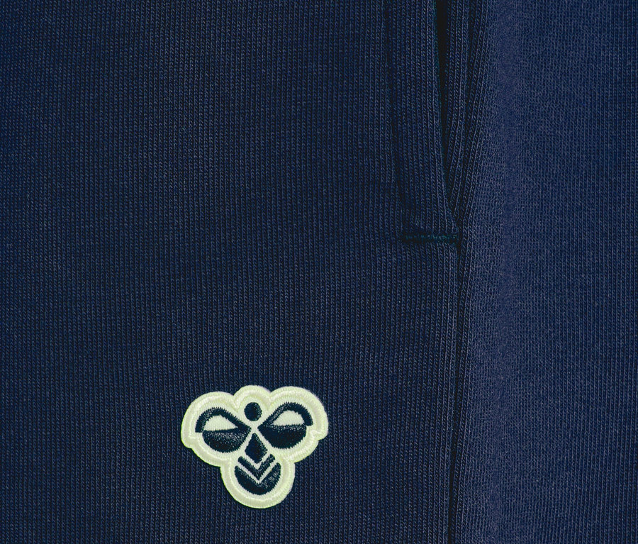 Gros plan sur un pantalon de survêtement bleu marine avec le logo Hummel.
