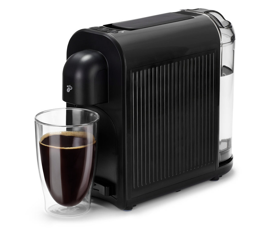 Une machine à café noire Cafissimo now black à côté d'un verre de café.