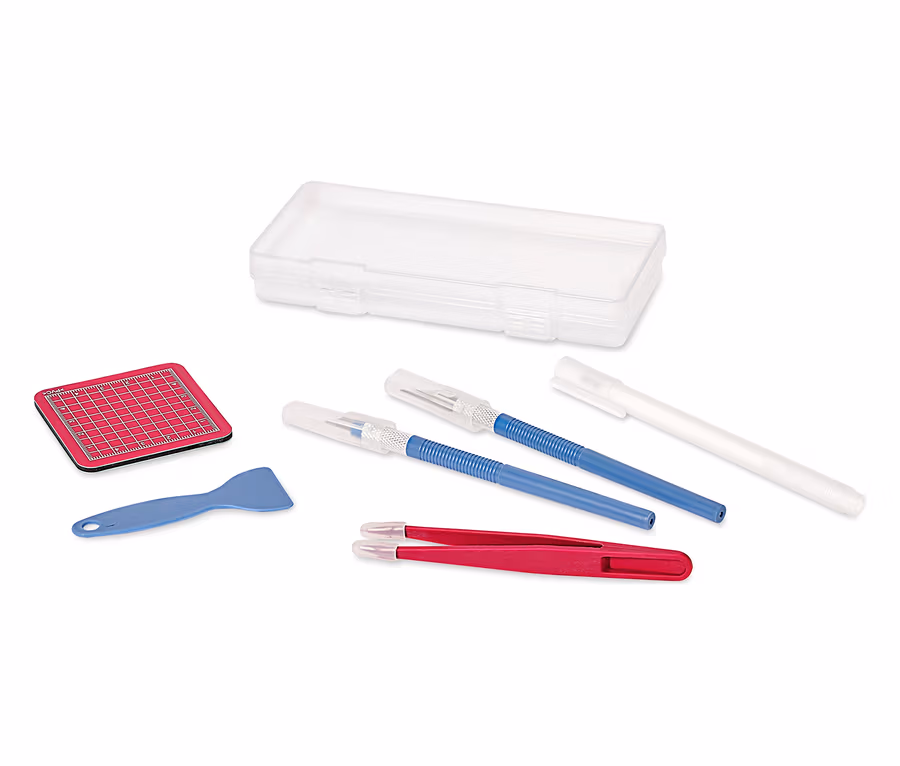 Un ensemble d'artisanat avec un tapis de découpe, un grattoir, une pince à épiler, un cutter et une boîte de rangement sur fond blanc.