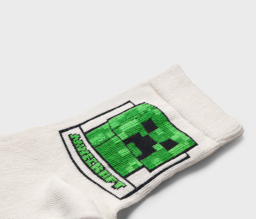Gros plan d'une chaussette blanche avec un motif Minecraft Creeper vert.