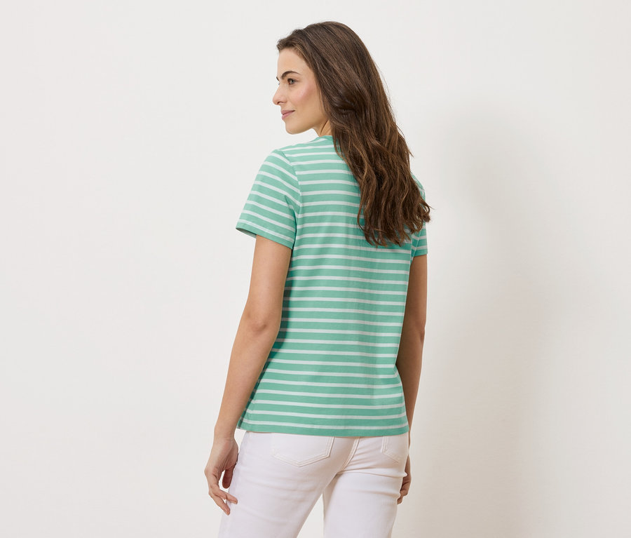 Femme vue de dos portant un t-shirt turquoise rayé et un pantalon blanc.