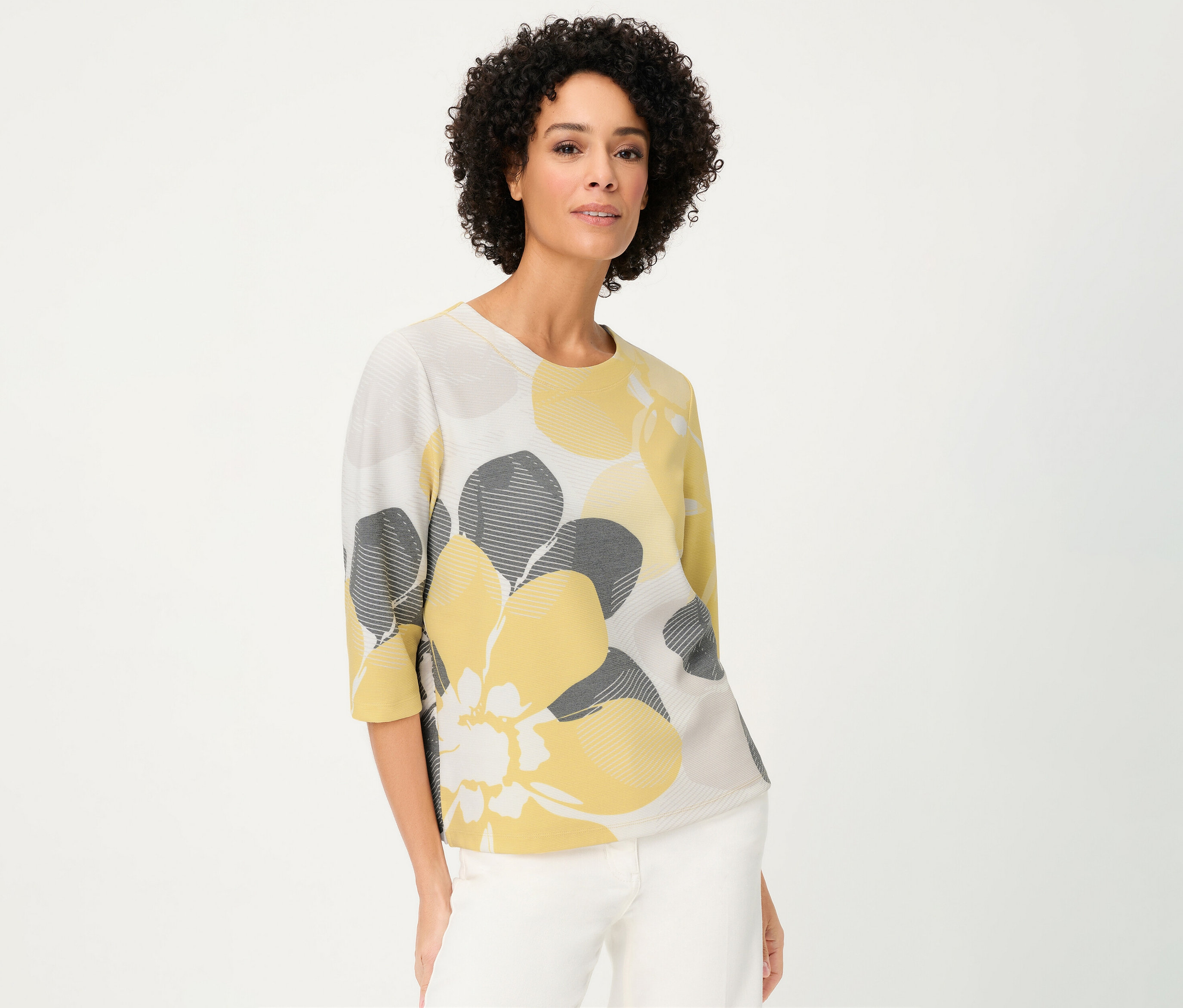 Une femme porte un sweat-shirt Olsen « Ottoman » à fleurs jaunes et grises sur fond blanc.