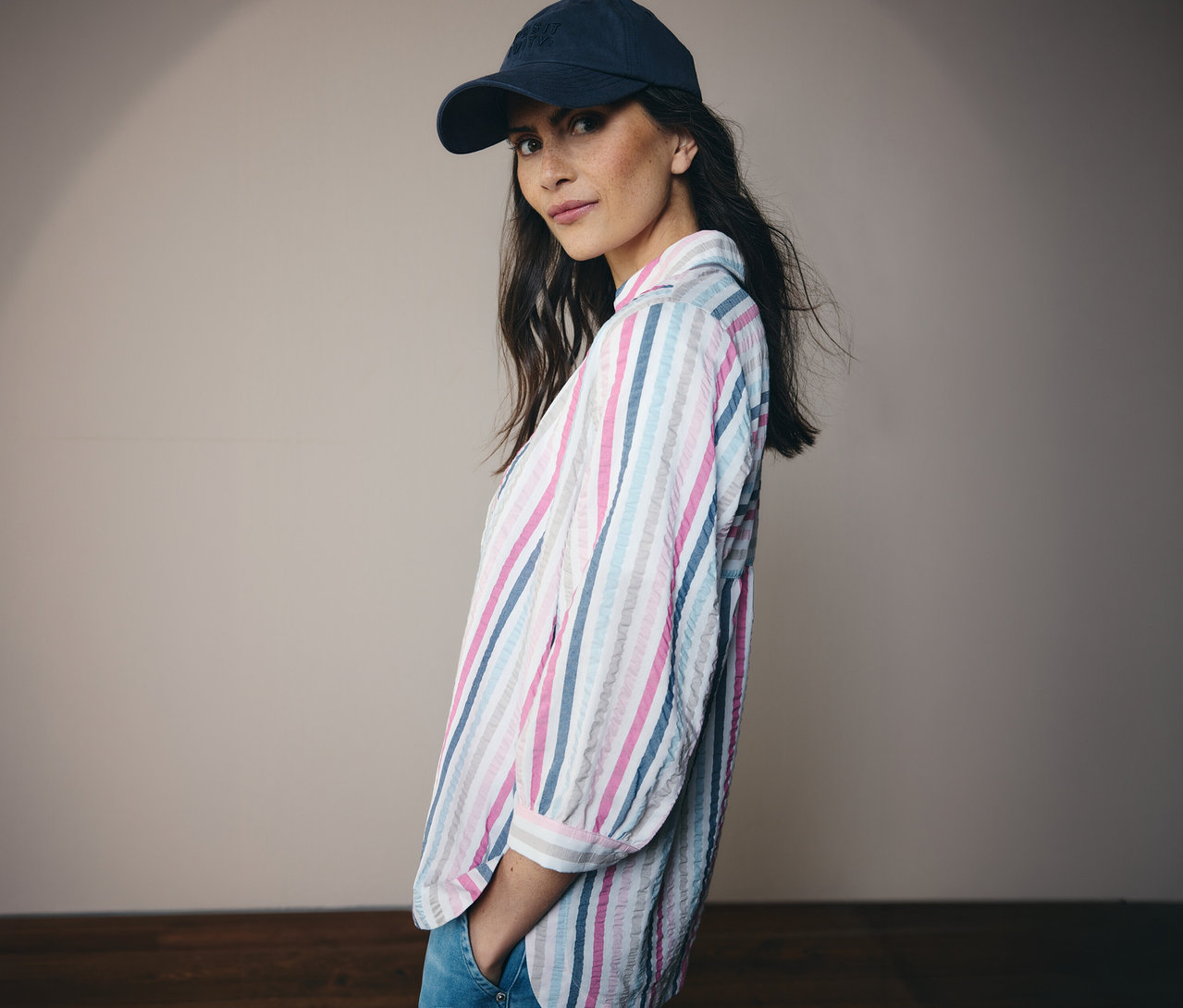 Femme portant un chapeau bleu et un chemisier CECIL rayé regardant la caméra.