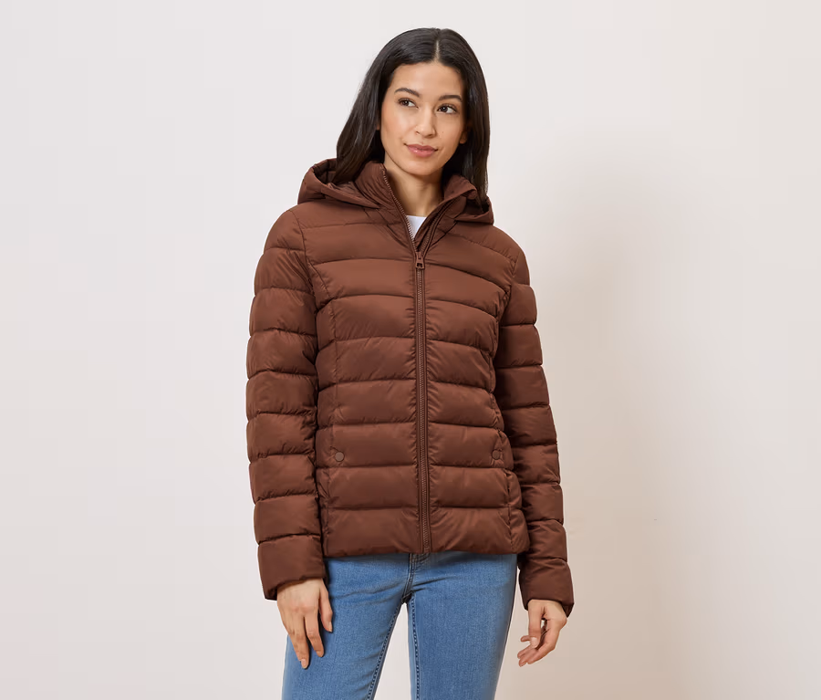 Une femme portant un jean et une veste marron à capuche sur un fond clair.