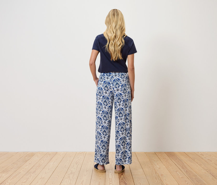 Vue de dos d'une femme blonde portant un t-shirt bleu marine et un pantalon à motifs bleus et blancs.