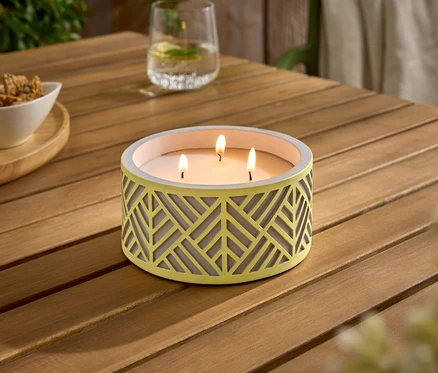 Une table en bois avec une bougie jaune allumée, un bol de collations et deux verres.