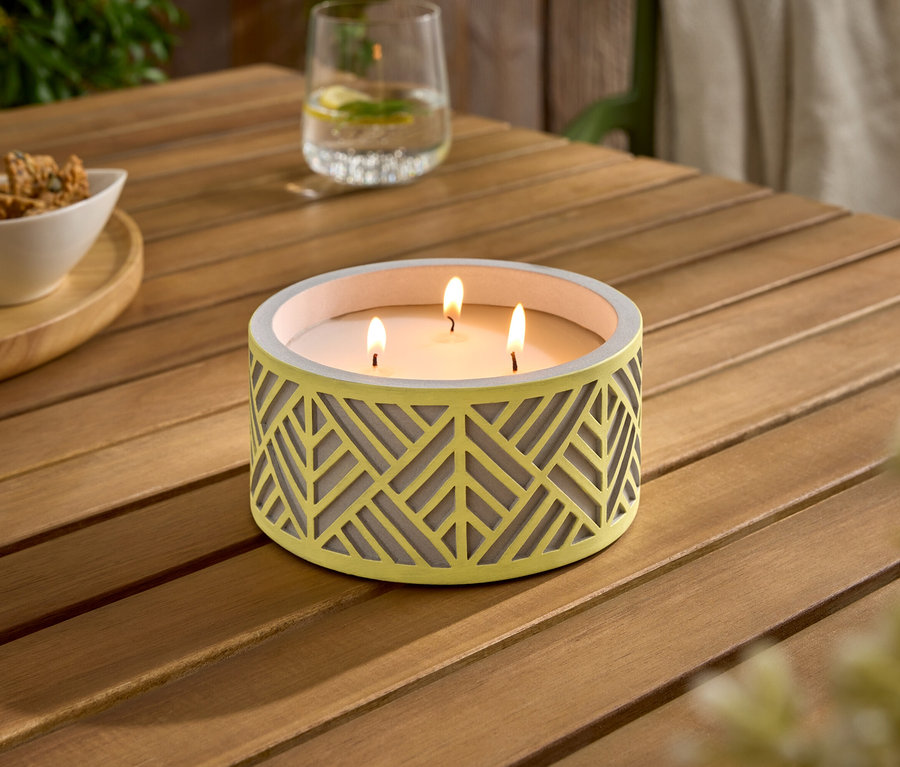 Une table en bois avec une bougie jaune allumée, un bol de collations et deux verres.