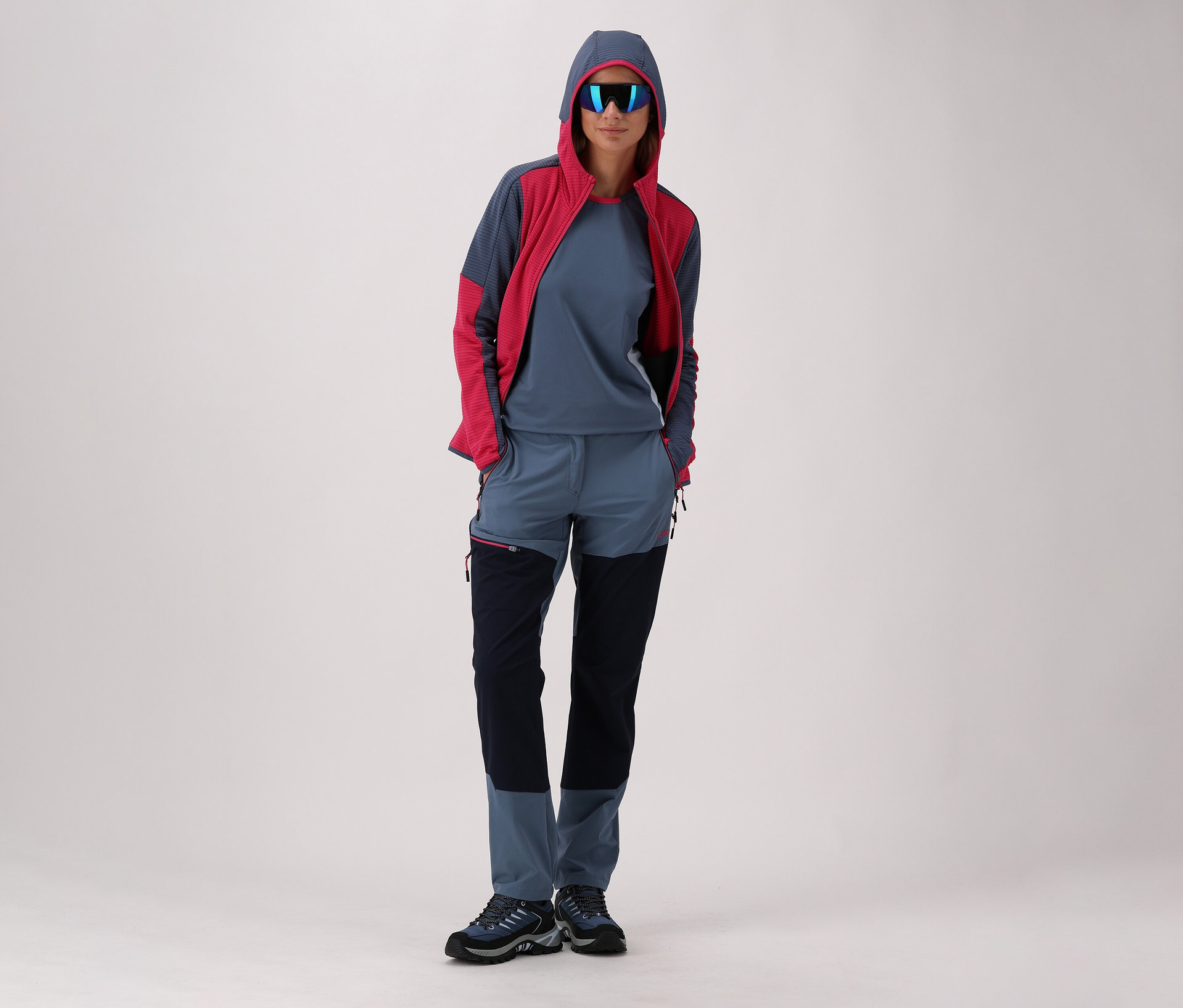 Femme portant des lunettes de soleil, une veste polaire CMP pour femme avec capuche et des chaussures de trekking CMP pour femme RIGEL LOW 2.0 WP, bleu.