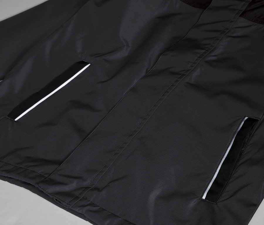 Gros plan d'une veste noire avec des poches finies par une bande réfléchissante.
