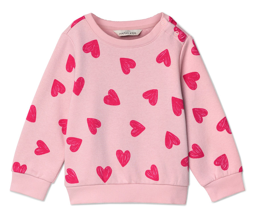 Un pull rose clair avec un motif de cœurs rouges posé à plat sur une surface blanche.