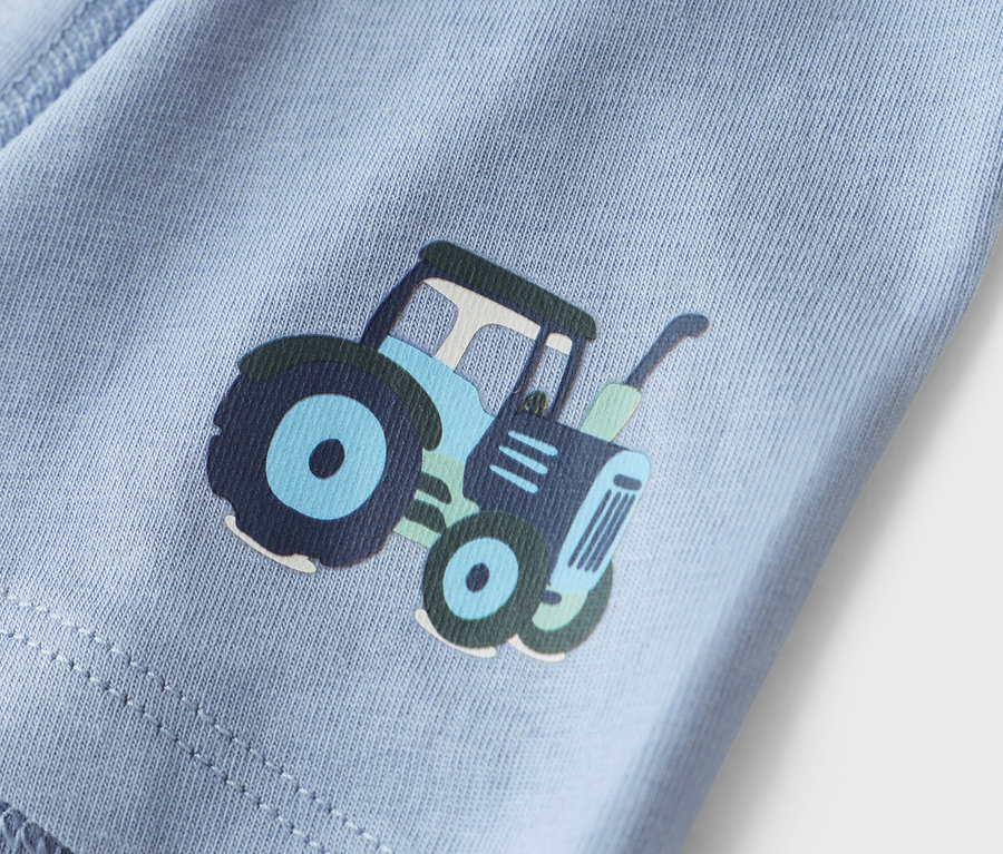 Gros plan sur un tissu bleu clair avec un imprimé de tracteur.