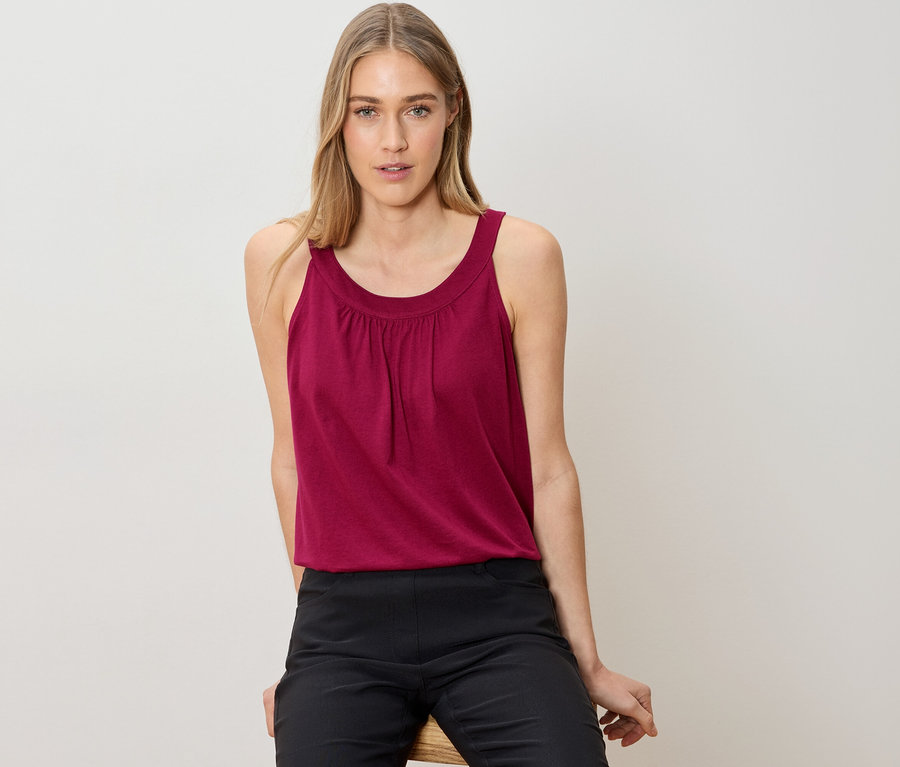 Femme assise portant un débardeur et un pantalon noir.