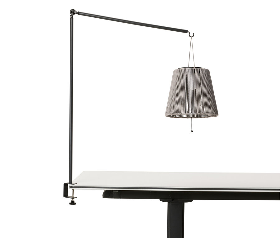 Lampe suspendue grise au-dessus d'une table blanche, fixée à une barre noire.