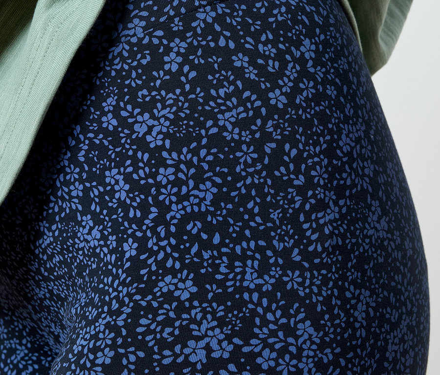 Gros plan d'une personne portant des leggings à fleurs bleues et un haut vert clair.