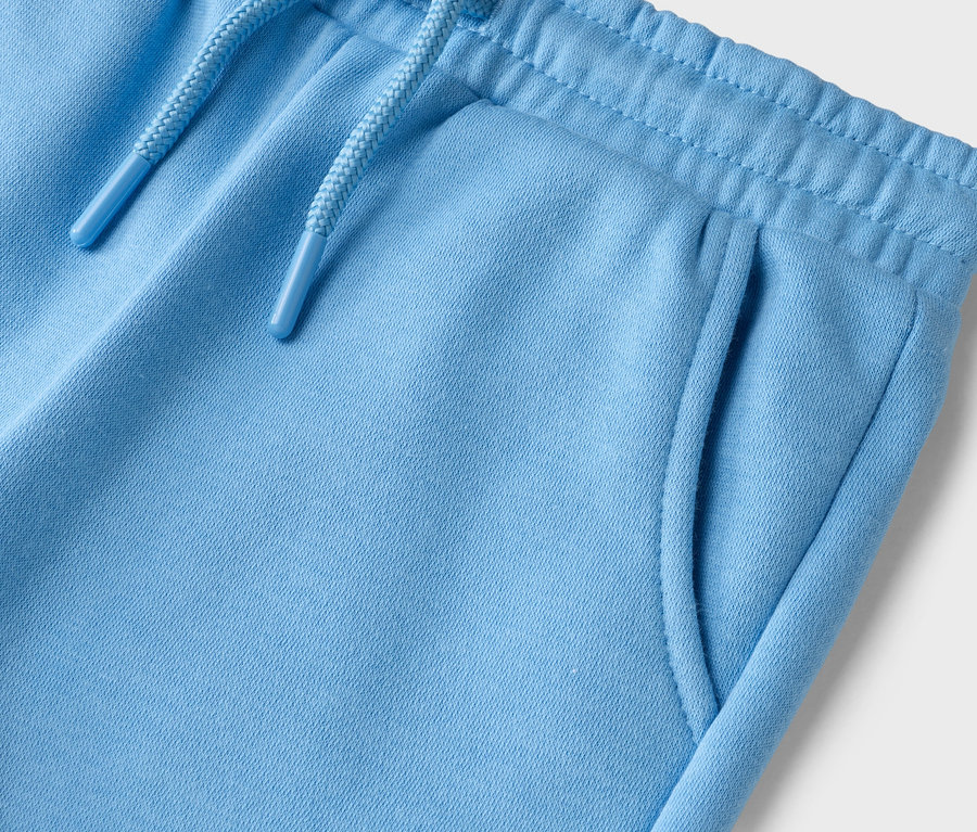 Gros plan du haut d'un pantalon de survêtement bleu clair avec cordon de serrage et poches.
