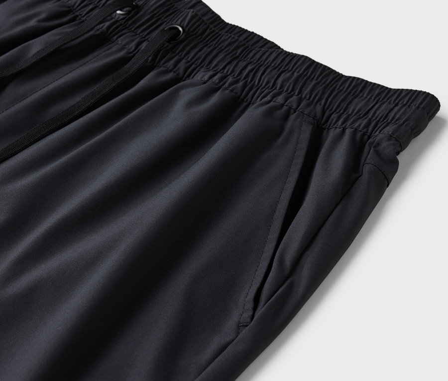 Gros plan d'un pantalon de survêtement noir avec une taille élastique et un cordon de serrage.