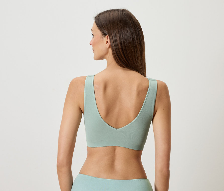 Vue de dos d'une femme aux longs cheveux bruns portant un soutien-gorge et des sous-vêtements vert clair.