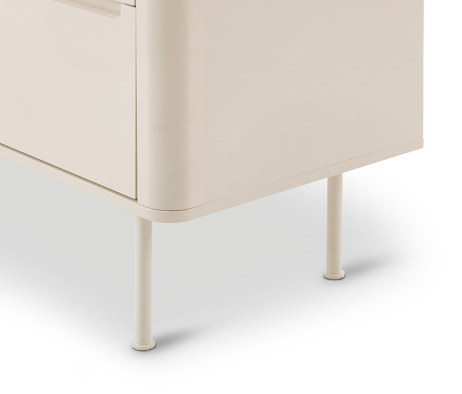 Coin inférieur droit d'une armoire beige clair aux bords arrondis, reposant sur deux pieds cylindriques fins sur un fond blanc.