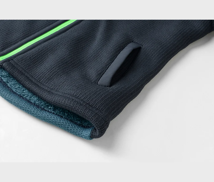 Gros plan d'une manche bleu foncé avec une bande vert vif, une ouverture de poche et une doublure moelleuse bleu clair.