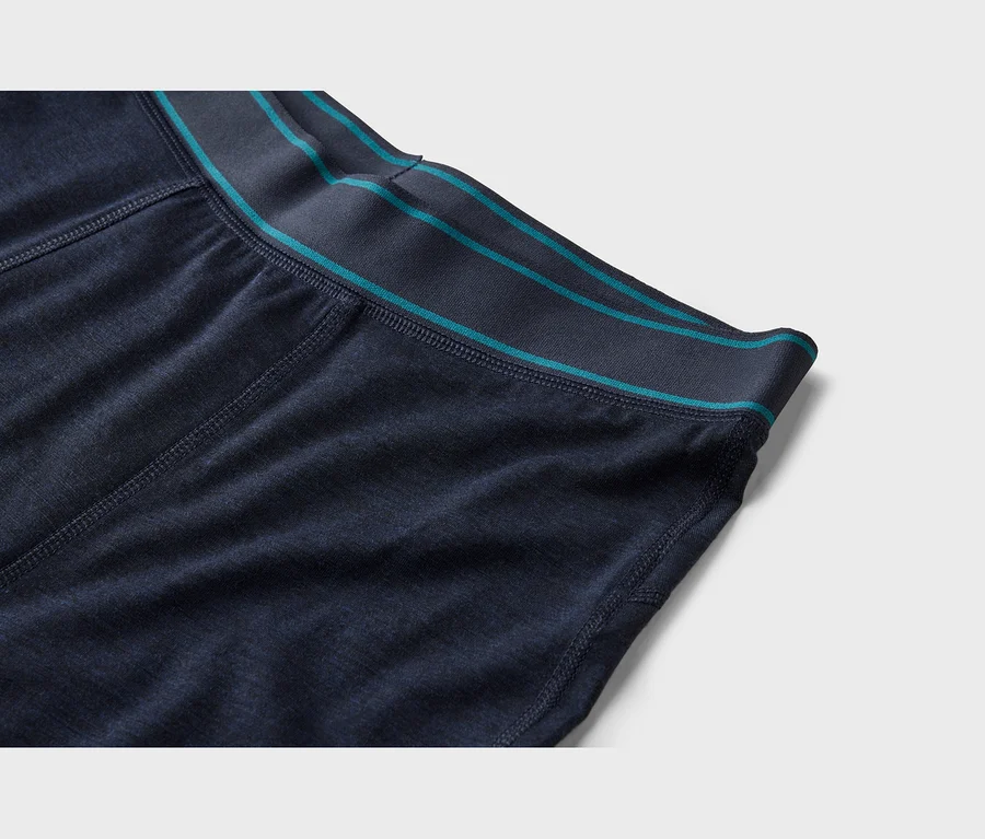Gros plan d'un tissu bleu foncé avec une ceinture gris foncé ornée de deux fines rayures sarcelle et de coutures visibles.
