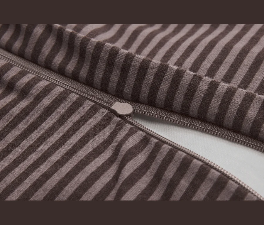 Gros plan d'un tissu rayé marron et beige avec une fermeture éclair partiellement ouverte et un curseur visible.