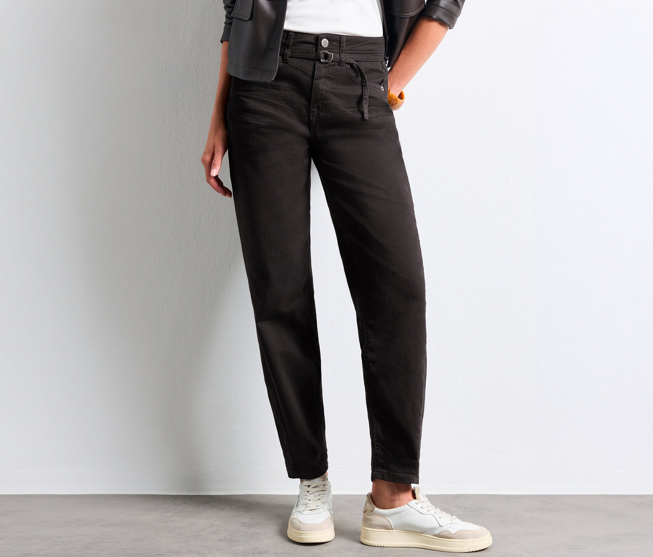 Personne portant un jean Barrel Street One noir taille haute avec un détail à nouer, un haut blanc, une veste en cuir noire et des baskets blanches.