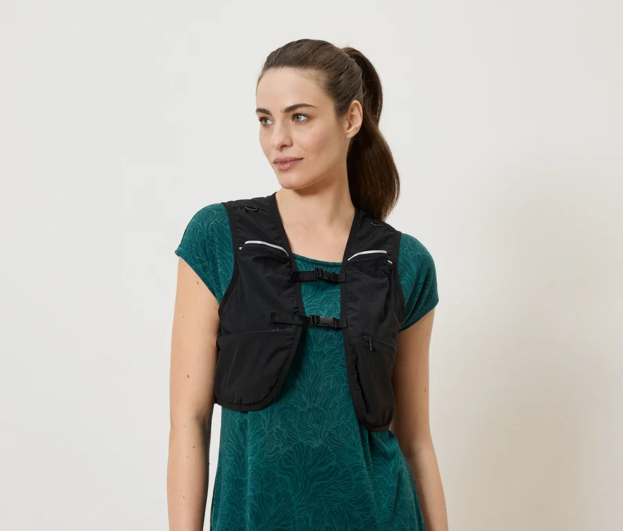 Femme portant un gilet de course noir sur une robe verte.