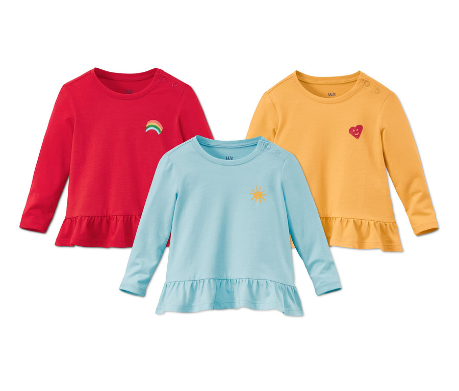 Trois t-shirts à manches longues en coton bio : rouge avec un arc-en-ciel, jaune avec un cœur et bleu clair avec un soleil.