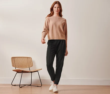 Une femme debout porte un pantalon de jogging noir avec nervure.