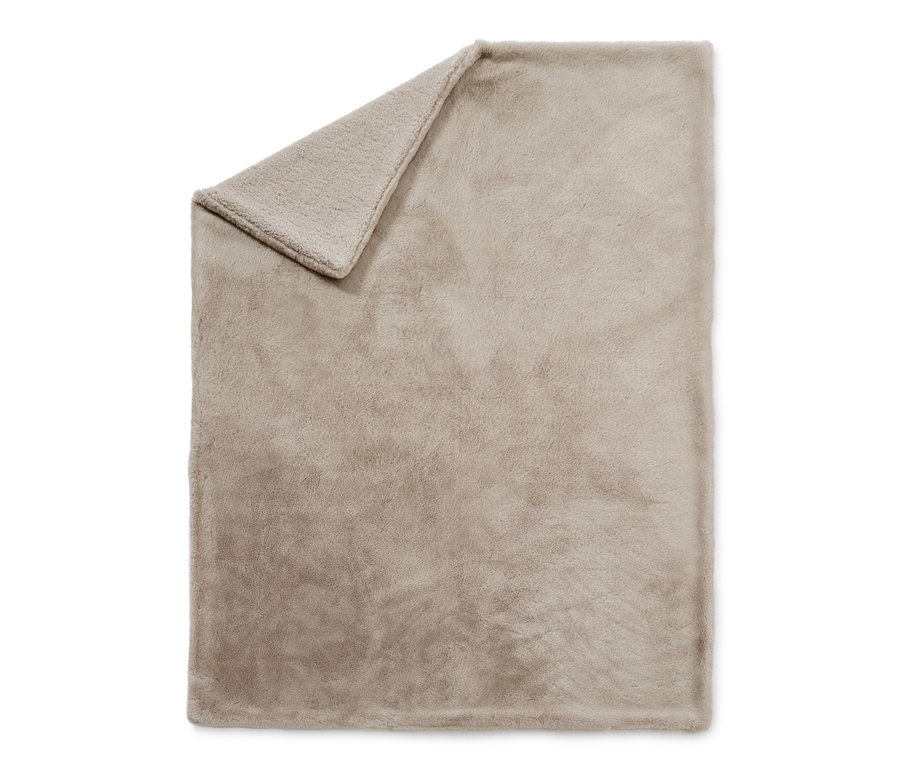 Couverture moelleuse en fourrure synthétique beige avec un coin plié.